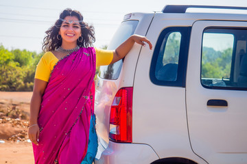relaxed indian woman in a traditional pink sari and costume jewelry on summer travel vacation to the coast towards the sea