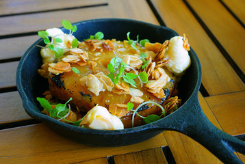 Slices of roasted caramelized pineapple in caramel sauce in a cast iron pan