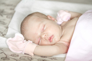 Close up of a sleeping naked newborn baby girl on a white blanket