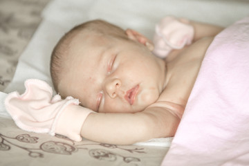 Close up of a sleeping naked newborn baby girl on a white blanket