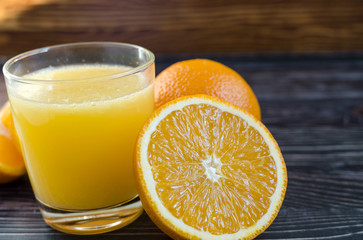 Orange juice and oranges on a dark background