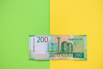 Two hundred ruble bill on a yellow paper background.