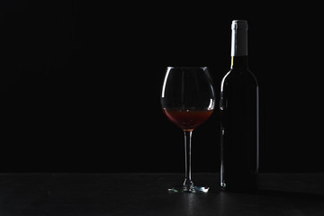 Bottles of wine and different glasses of wine on a dark background