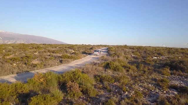 Aerial shot Following an old car on a dirt road in the countryside.