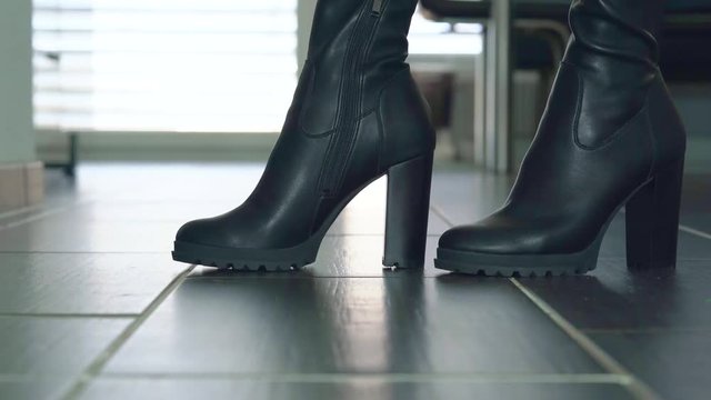Girl struts in front of the camera in black faux leather high heels block heel boots around
