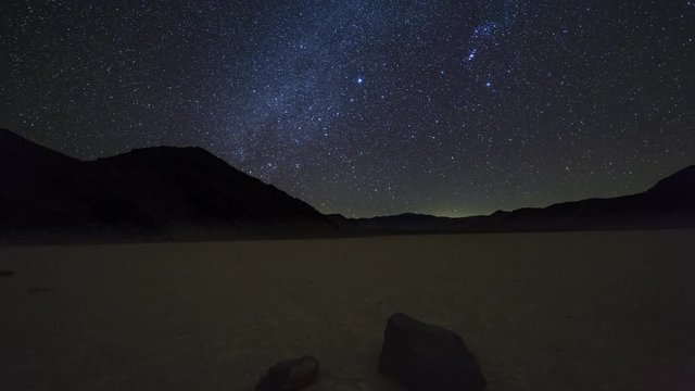 Inclined motion nighttime time lapse of the milky way over moving rocks on the Racetrack Playa