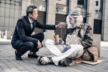 Helpful caring man in costume putting hand on shoulder of dirty homeless