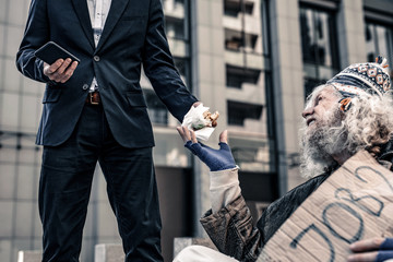 Desperate starving old man sitting on cold ground and begging for food