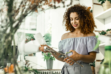 Young curly student feeling good while working in flowershop