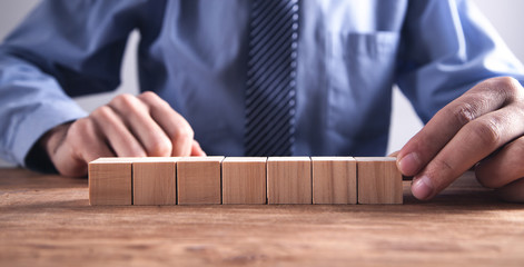 Businessman holding wooden cube on a wooden table.