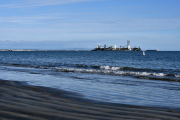 Oil drilling wasted darken the shoreline at Alamitos Beach