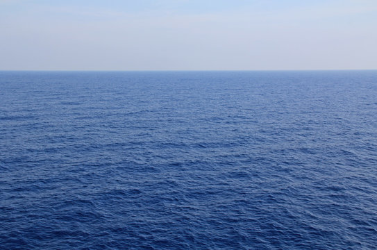 A textured background of the calm open water of the Agean sea with plenty of beautiful blue sky and water copy space.
