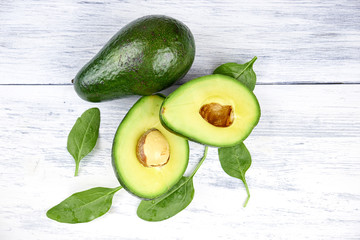 Slices of avocado on white background. Whole and half with leaves.