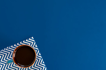 top view of cup of black coffe on blue background with copy space.