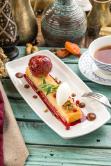 Apple sponge cake with ice cream and walnuts and cup of tea on blue wooden table