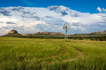 Farm scene with a wind pump and sandstone mountains