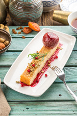 Apple sponge cake with ice cream and walnuts and cup of tea on blue wooden table