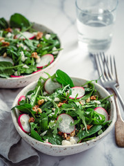 Vegan salad bowl with arugula, spinach, radish, coconut crumble or cottage cheese,walnut.Top view.Vegan breakfast, vegetarian food, diet concept. Two bowls with salad on white marble tabletop.Vertical