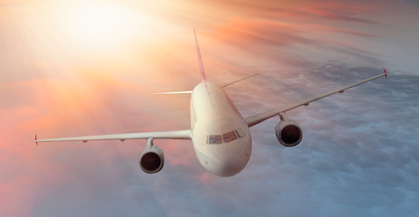 White Passenger airplane in the clouds at sunset - Travel by air transport