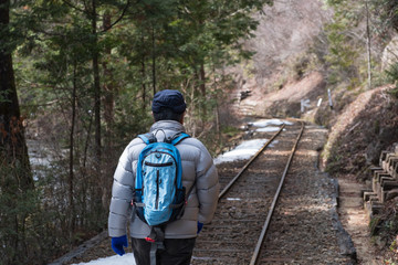 写真素材：線路を歩く男性　鉄道　廃線　休止　旅行　田舎　森林　