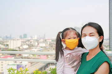 Mother carrying her daughter with wearing a protection mask against PM 2.5 air pollution in Bangkok...