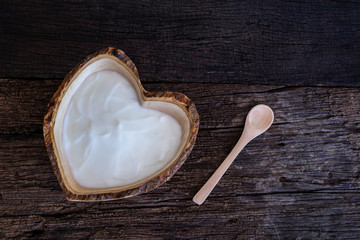 Natural homemade plain organic yogurt in wood bowl on wood texture background