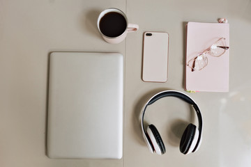 Flat lay of working desk of modern stylish freelancer with a laptop, smartphone, headphones and cup of coffee