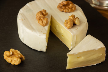 Camembert chopped in a dark background with nuts