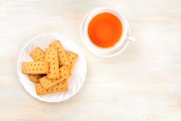 Scottish shortbread butter cookies, shot from the top on a white wooden background with tea and copy space