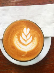 cup of coffee with cream on wooden background