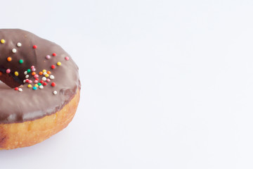 American donuts, glazed with melted chocolate and decorated with sprinkling, lie on a platter.