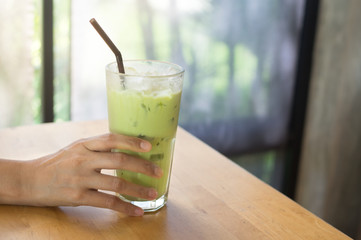 Iced green tea in woman hand.