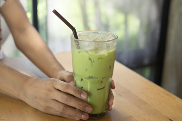 Iced green tea in woman hand.