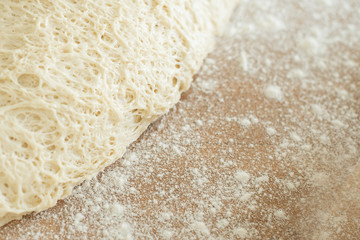 dough lying on a wooden cutting board sprinkled with flour