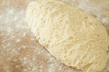 dough lying on a wooden cutting board sprinkled with flour