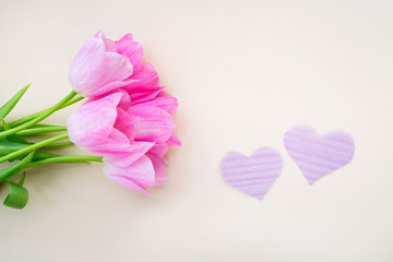 Composition of spring flowers and two hearts on a yellow background. View from above