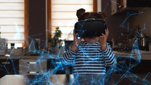 Child with virtual reality headset sitting behind table indoors at home and looking at the futuristic hologram structure