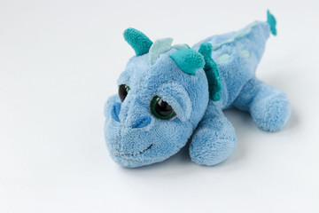 Children's soft toy blue dragon is located on a white background