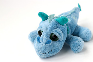 Children's soft toy blue dragon is located on a white background