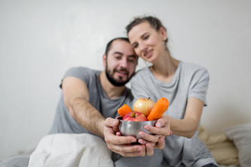 Happy couple holds a plate of vegetables in their hands. White background.