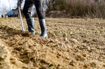 Male farmer working the soil, wearing rubber boots