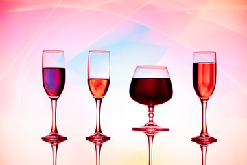 Four wine glasses of water are on the table, behind a colorful background.Glasses reflected in the glass.