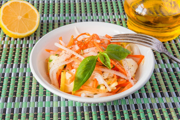 Vegetarian appetizer - Salad with radish daikon with apples and carrots in a bowl and a fork on a bamboo napkin