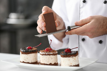 Male confectioner decorating tasty dessert in kitchen, closeup
