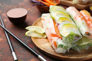 Plate with tasty spring rolls on table