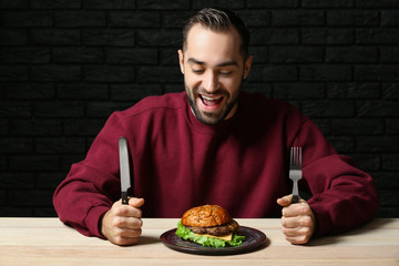 Man with tasty burger at table