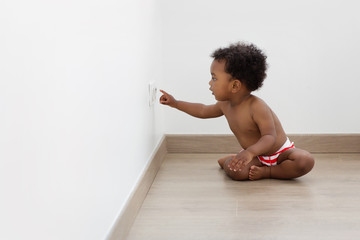 Baby sitting on the floor touching electrical plug