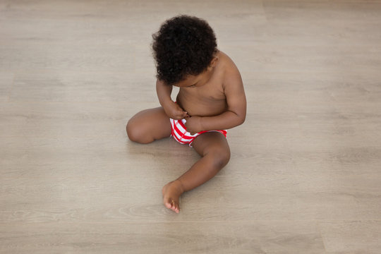 Black baby boy touching his belly button