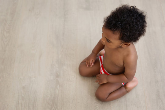 Overhead view of black baby boy keeling on wooden floor