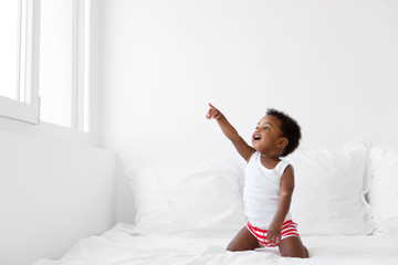 Toddler boy looking out by the window pointing with finger
